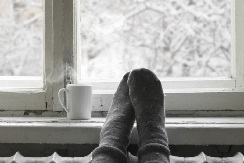 Coffee mug in front of a window with snowy scenery..