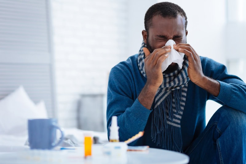 Man sneezing into tissue.